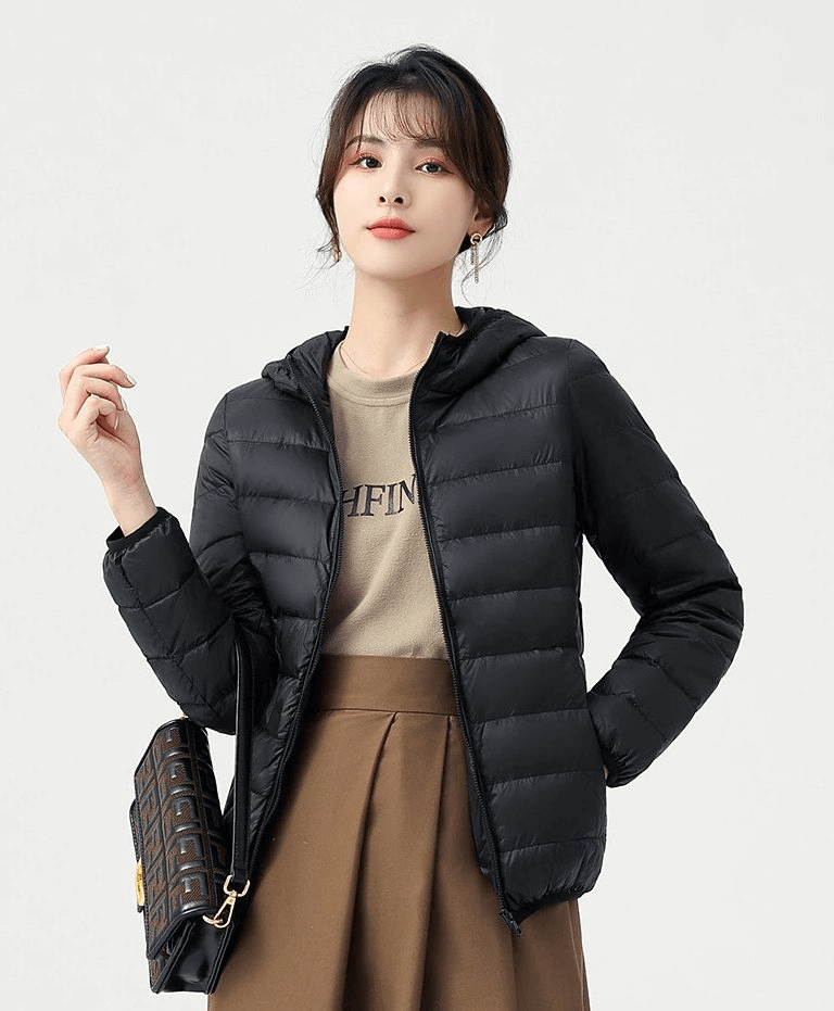 Woman wearing a stylish black down jacket with hood, perfect for outdoor activities; lightweight, windproof, and waterproof design.